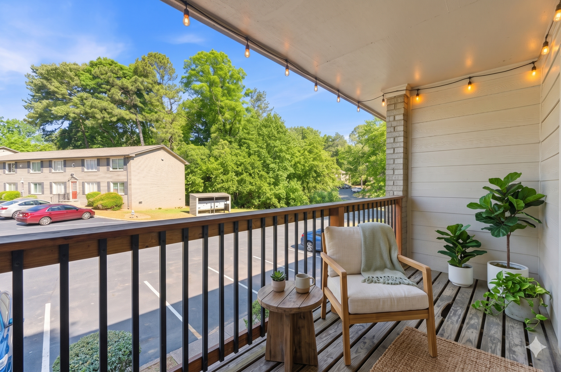 Porch seating with string lights, potted plants, and a view of apartments and trees across the street
