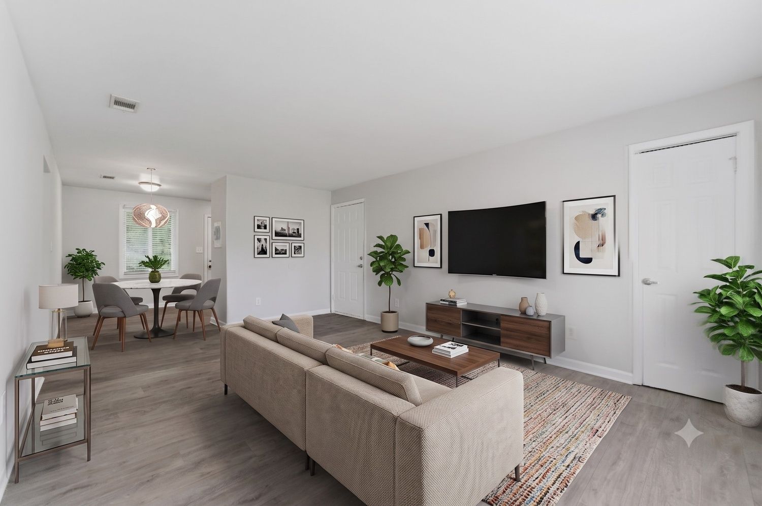 Modern living room with beige sectional, wall-mounted TV, dining area, and plants in a bright open layout