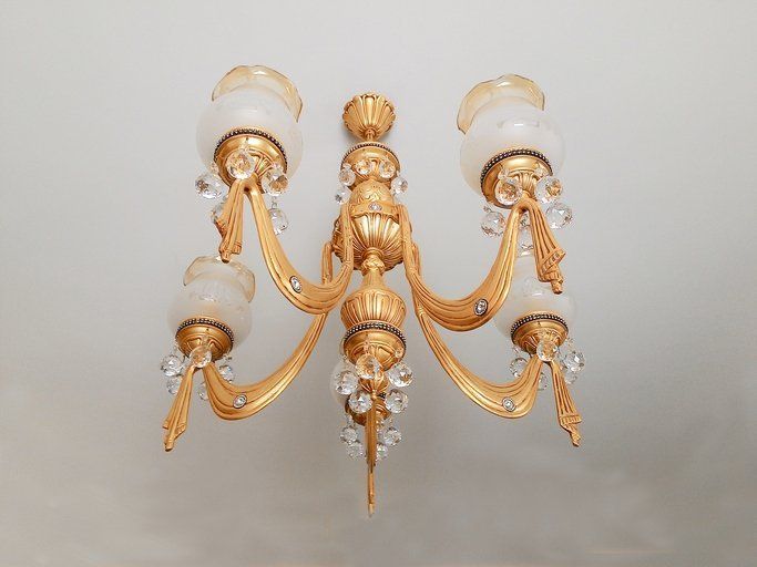 Gold chandelier hanging from white ceiling; The Shade Tree in Houston, TX