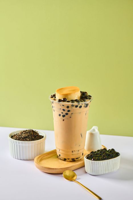 Iced coffee drink with whipped topping on a coaster, flanked by two small bowls, against a green background