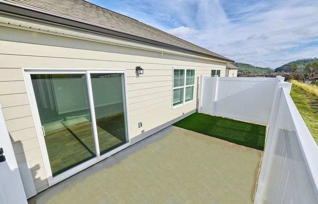 A patio with sliding glass doors and a white fence in front of a house.