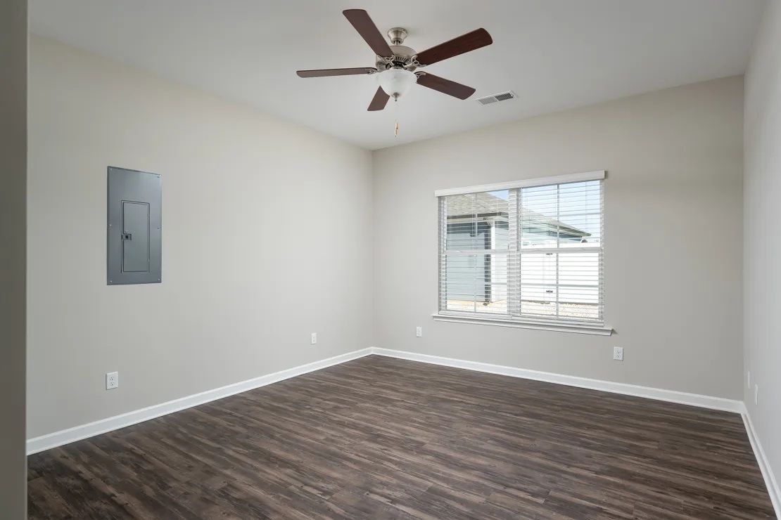 An empty room with a ceiling fan and a window.
