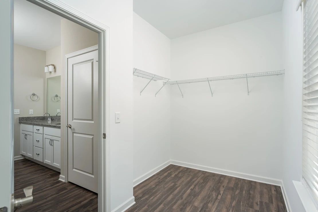 An empty living room with a ceiling fan and a window.