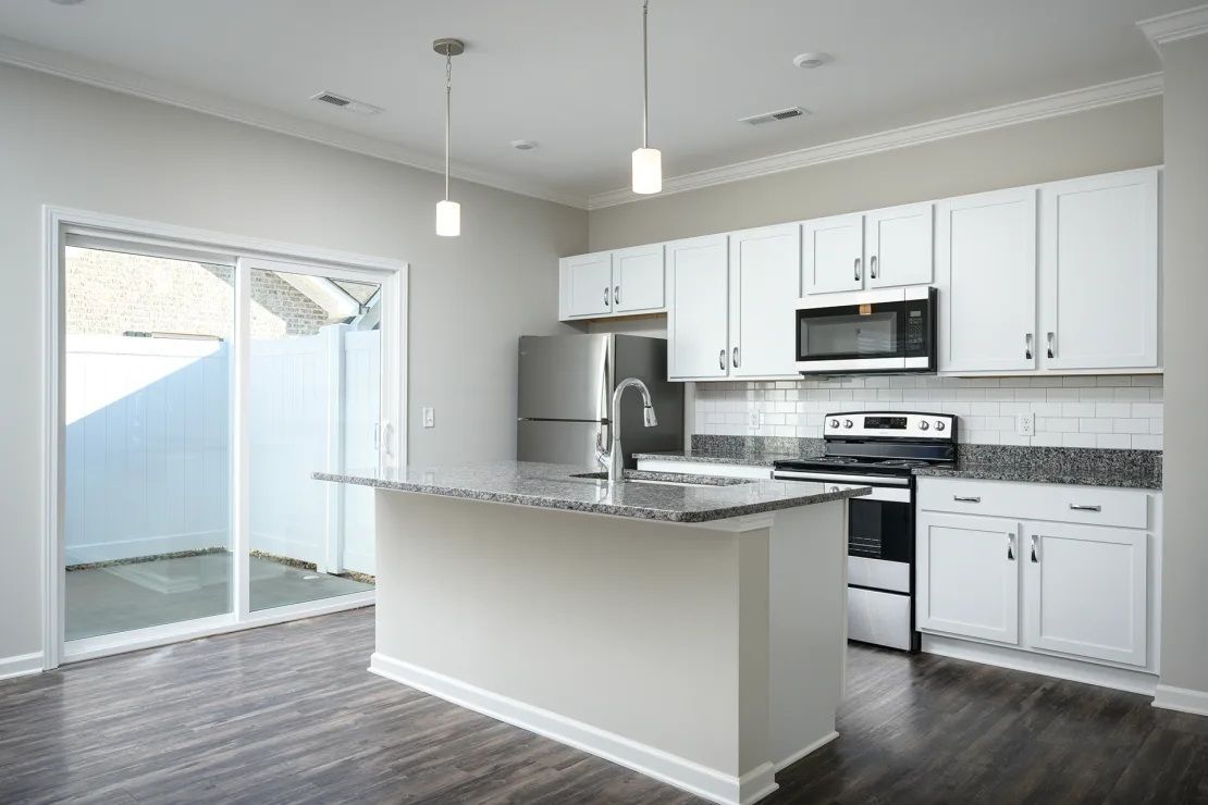 An empty kitchen with white cabinets and stainless steel appliances.