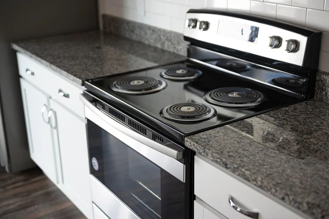 A kitchen with a stove top oven and granite counter tops.