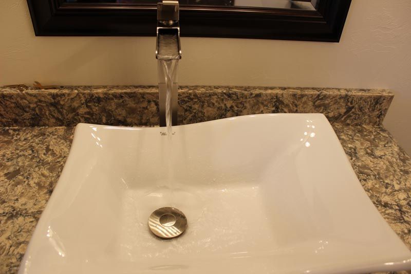 White bathroom sink with running faucet and granite countertop