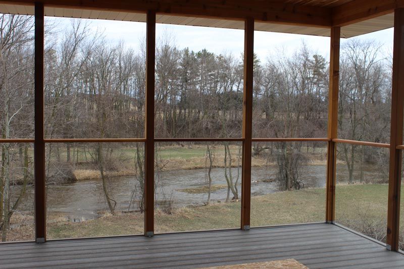 Wooden porch overlooking a leafless riverside landscape on an overcast day