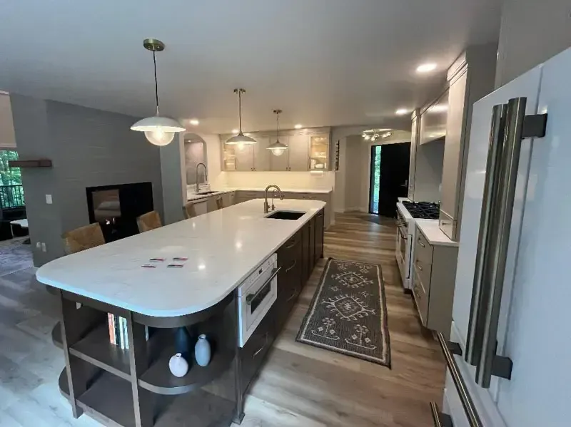 Modern kitchen with large white island, gray cabinets, stainless appliances, and hardwood floors.