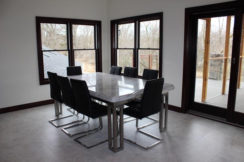 Modern dining room with black table and chairs beside large windows and glass doors