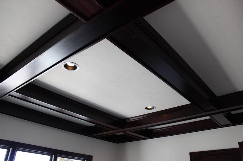 Ceiling with dark wooden beams and a white recessed panel with two lights