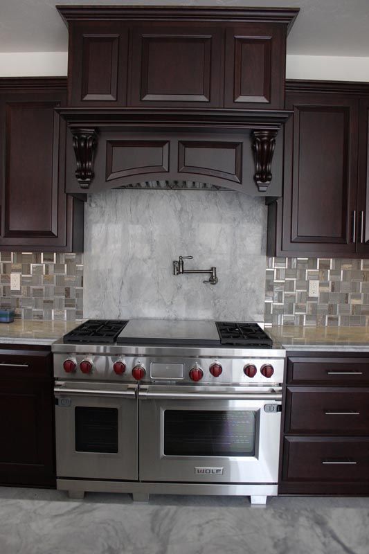 Modern kitchen with stainless steel range, dark wood cabinets, and tiled backsplash
