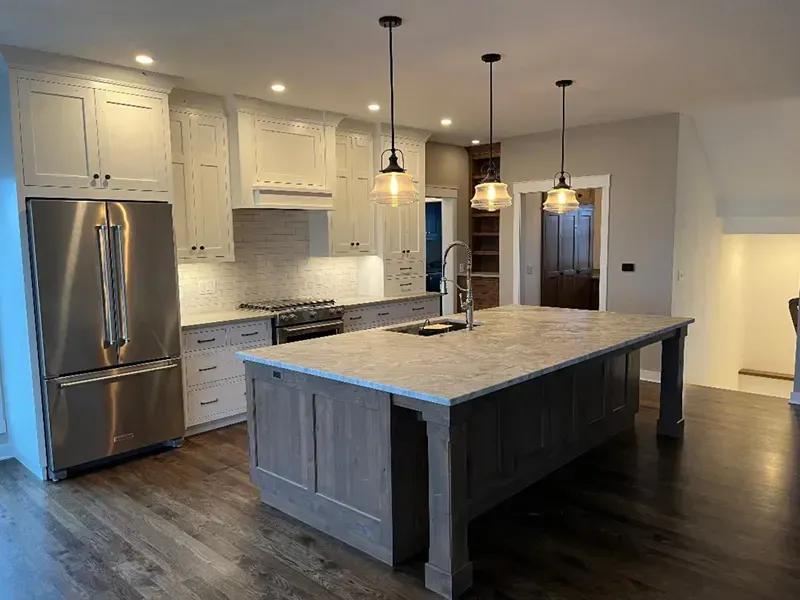 Modern kitchen with white cabinets, stainless steel fridge, large island, and dark wood floor