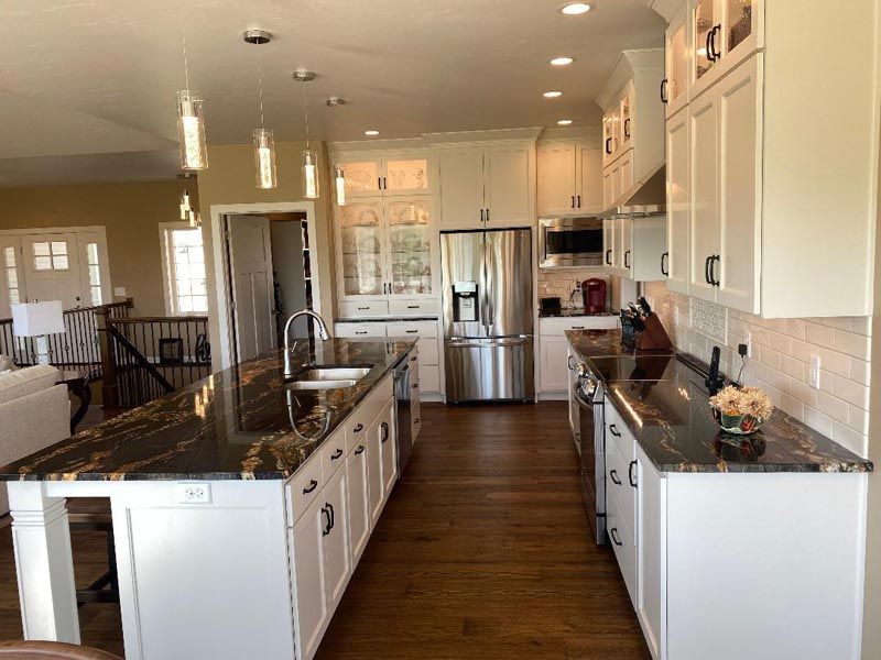 Bright modern kitchen with white cabinets, granite island, stainless steel appliances, and wood floors
