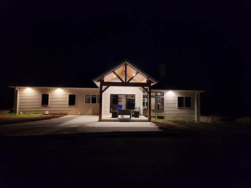 Lit building entrance at night with a covered porch and symmetrical wings