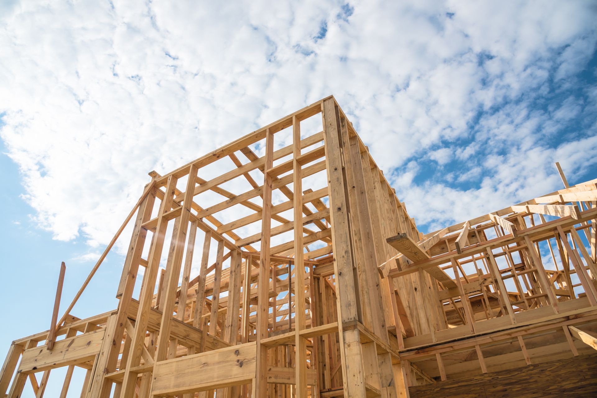 Wood-framed building under construction against a blue, cloudy sky