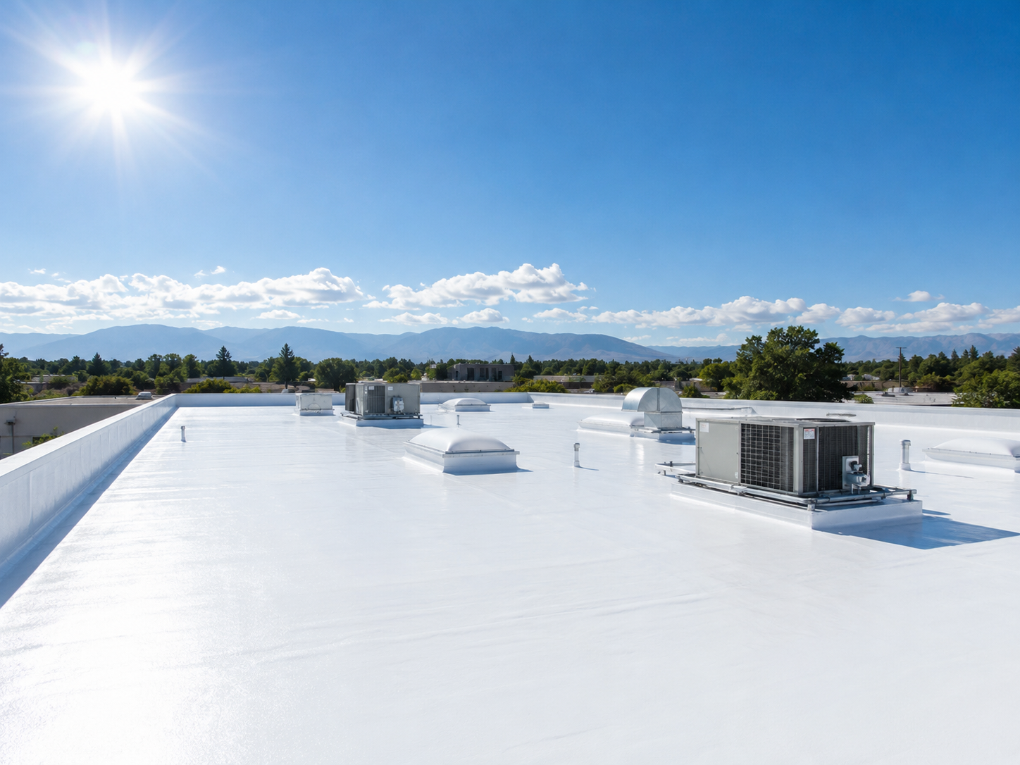 Bright white commercial rooftop with HVAC units under a blue sky and distant mountains