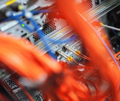 Close-up of tangled orange and blue network cables in a server rack