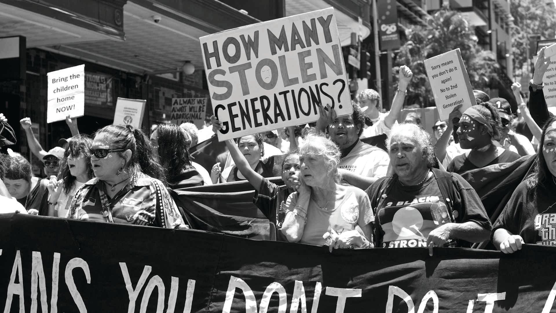 People marching in a protest, holding signs that read 