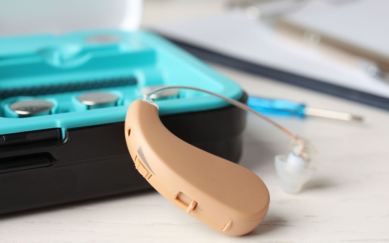A hearing aid is sitting on top of a blue case on a table.