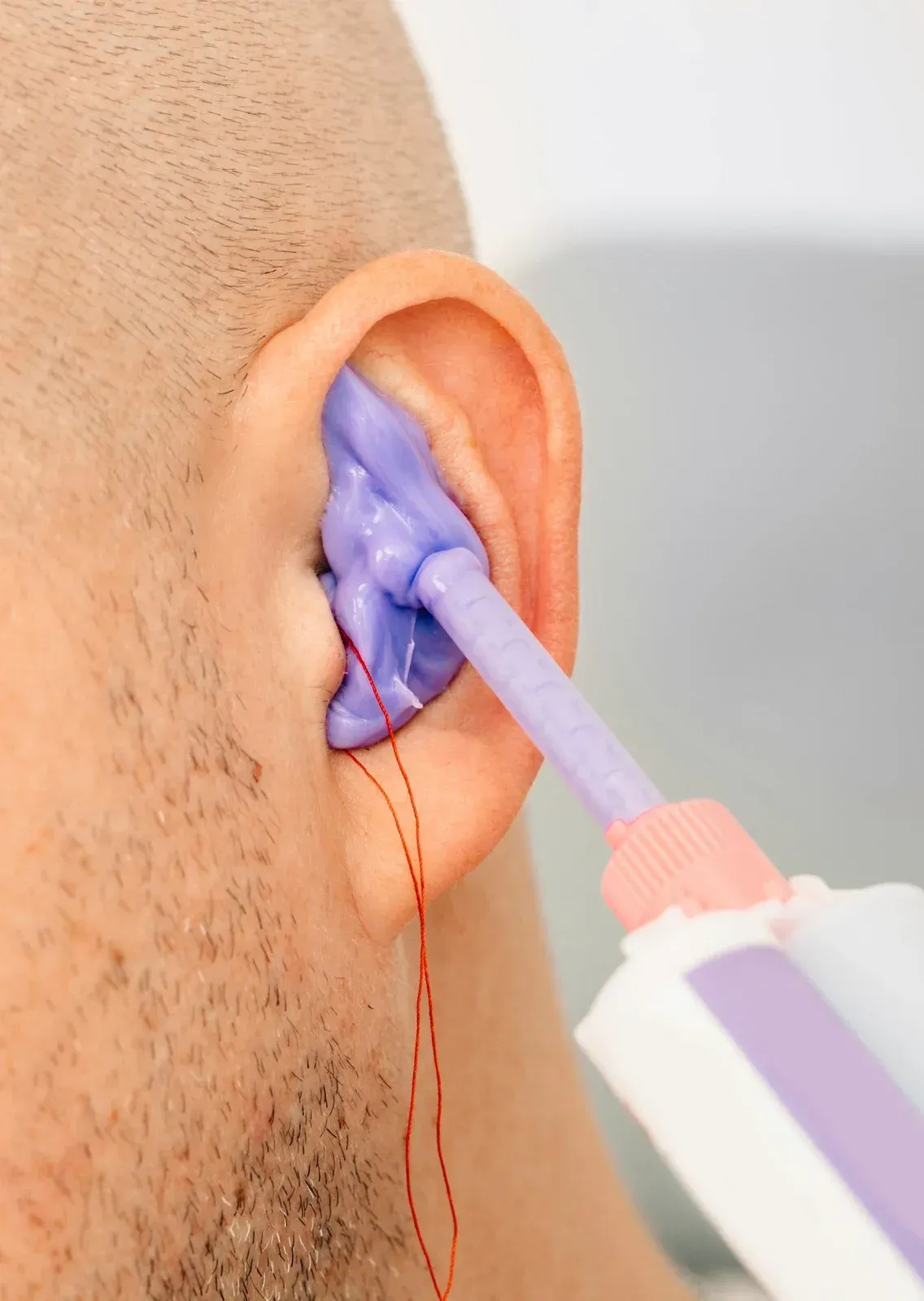 A man 's ear is being cleaned with a purple brush