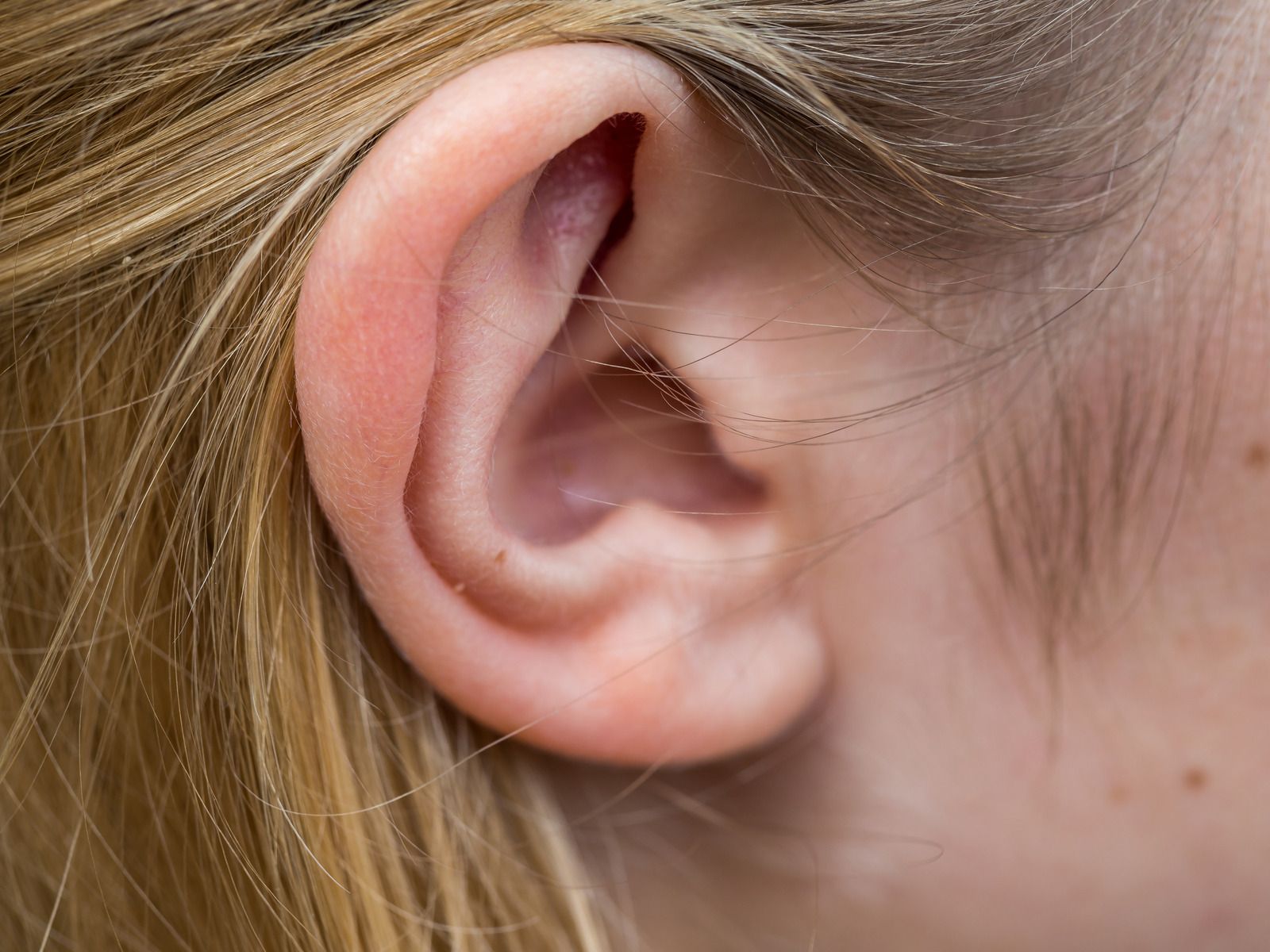 A close up of a woman 's ear with blonde hair.