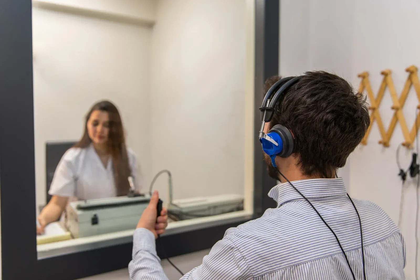A man wearing headphones is sitting in front of a mirror.