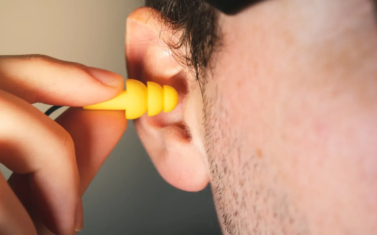 A man is putting ear plugs in his ear.