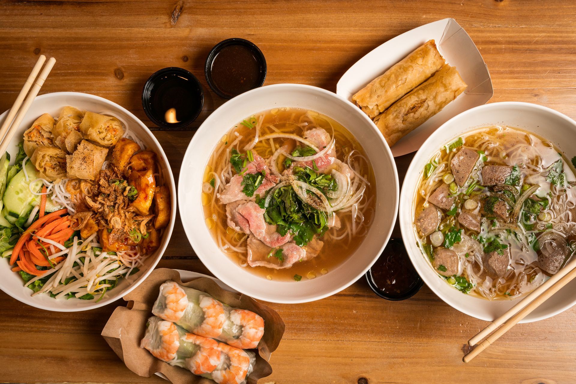 Bowl of Korean noodle soup topped with sliced beef and green onions on a wooden table