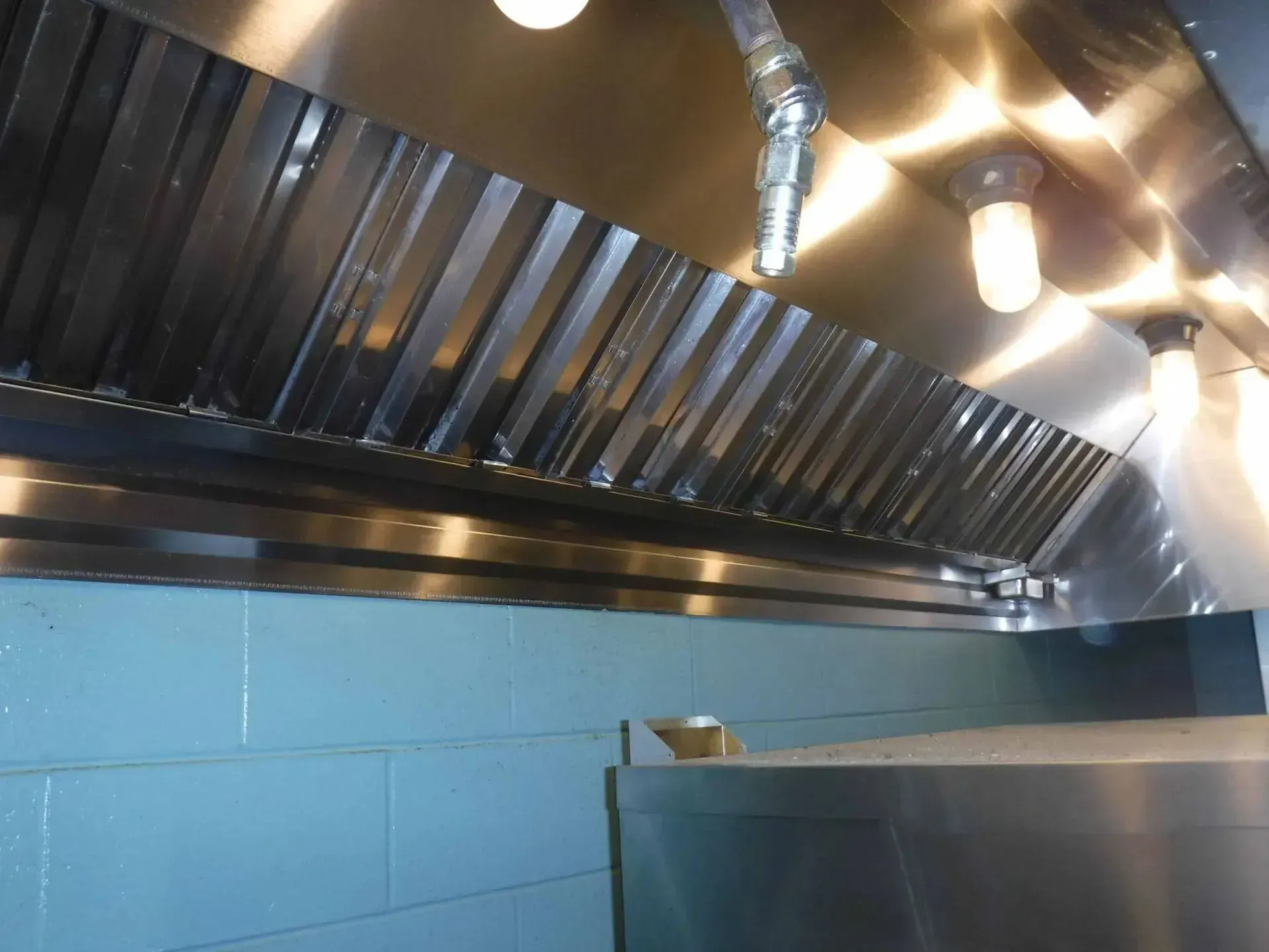 A stainless steel hood with a light hanging from it A stainless steel hood with a light hanging from it