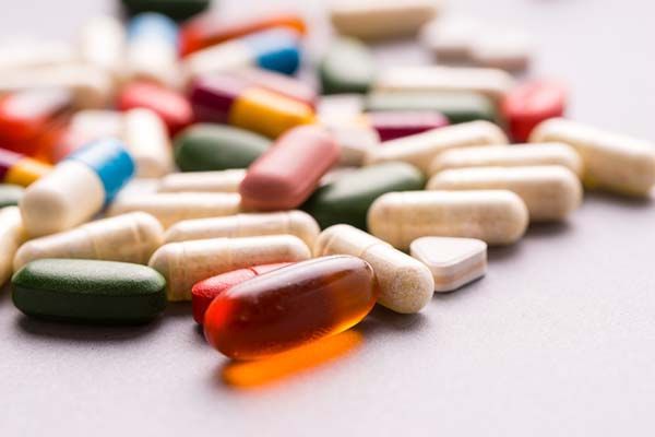 A pile of multicolored capsules and tablets scattered on a neutral surface.