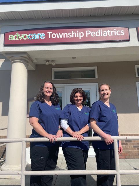 Three women standing in front of a sign that says Advocare Township Pediatrics.