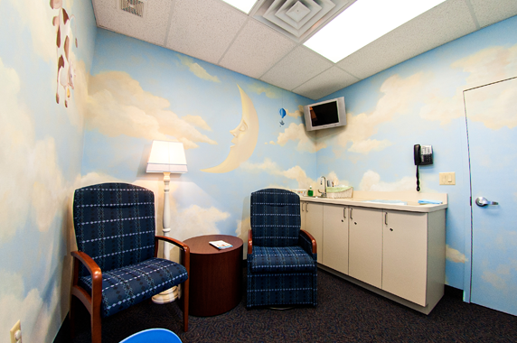 Two chairs and a table in a room with a painting of clouds on the wall