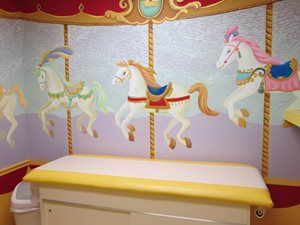 A doctor 's table with a carousel painting on the wall behind it.