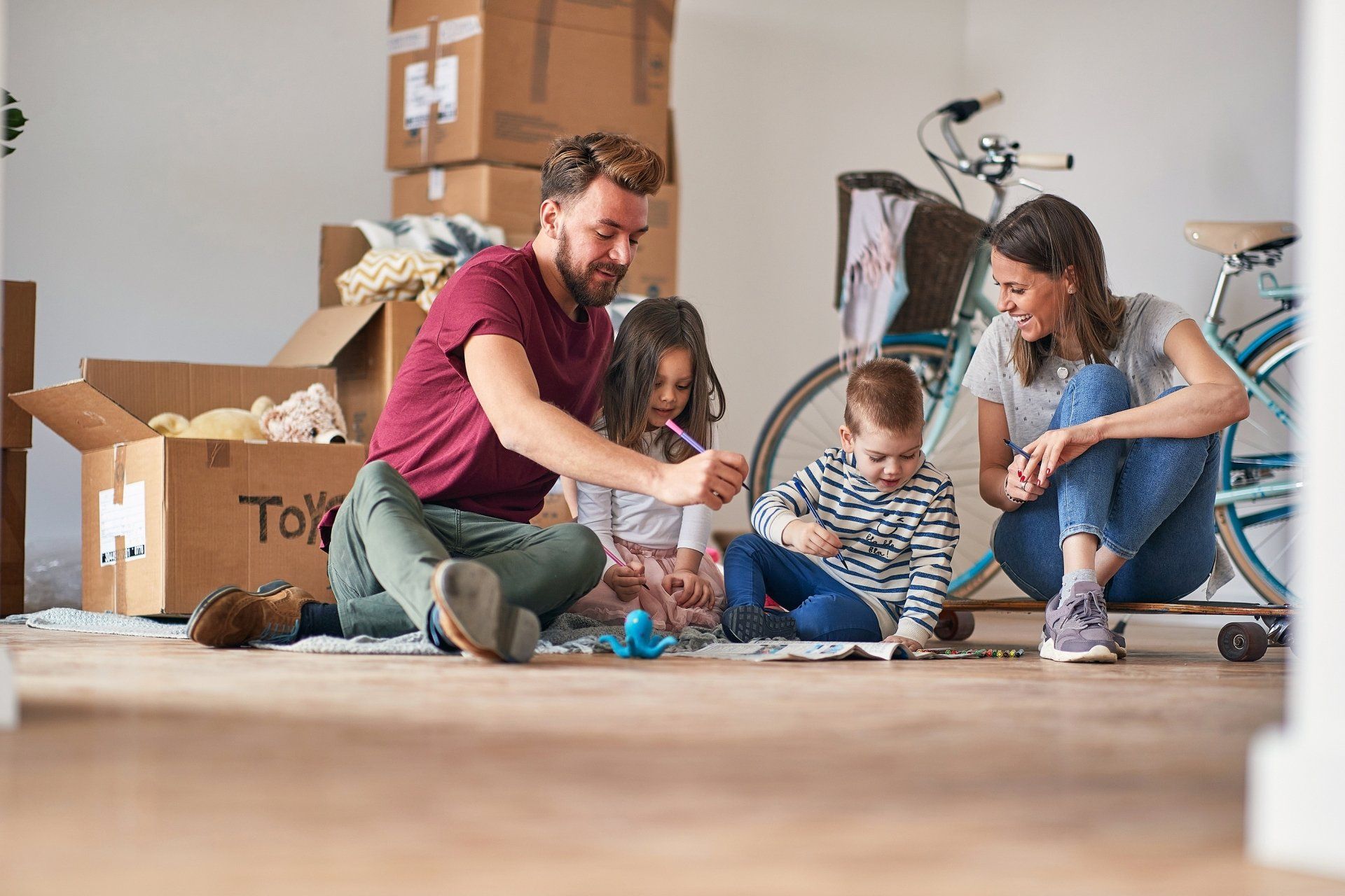 Family sitting on the floor opening a box together in a bright living room