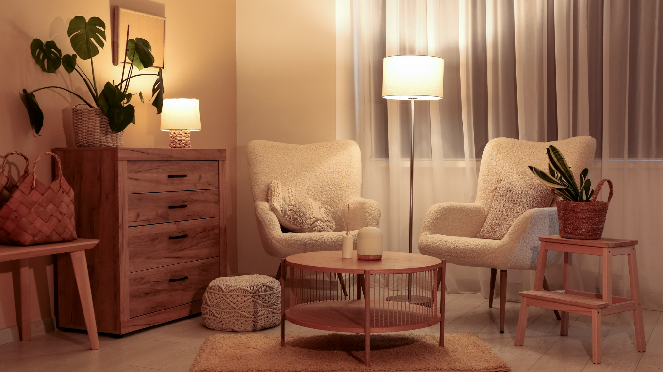 Cozy living room with beige chairs, wooden table, soft lamp light, and potted plants