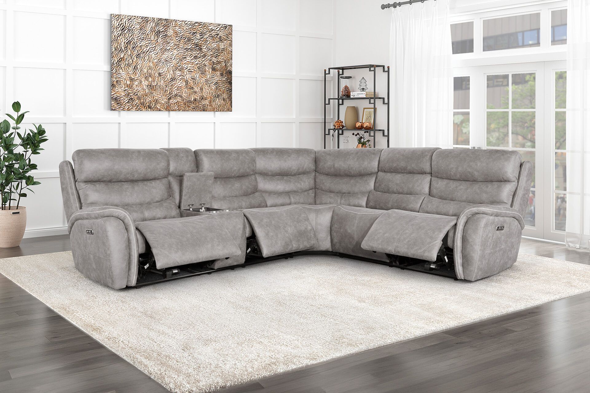 Gray sectional sofa in a bright living room with a white rug, plant, wall art, and shelving unit.