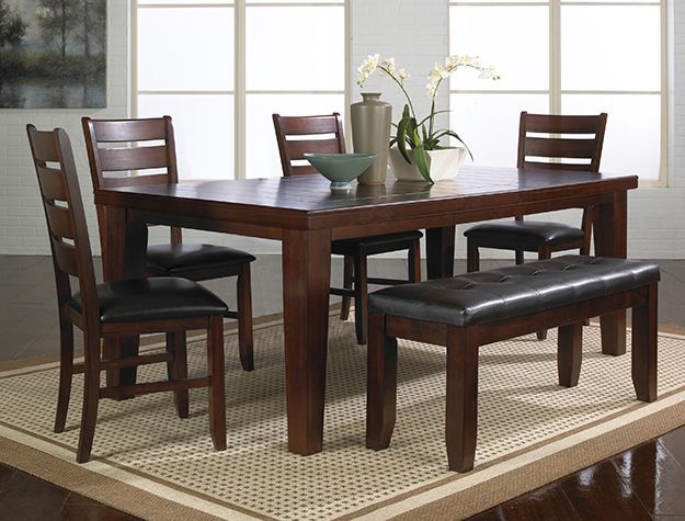 Dark wood dining table with four chairs and a bench in a bright room