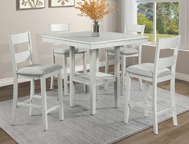 White dining table with four chairs on a light gray rug in a bright room.