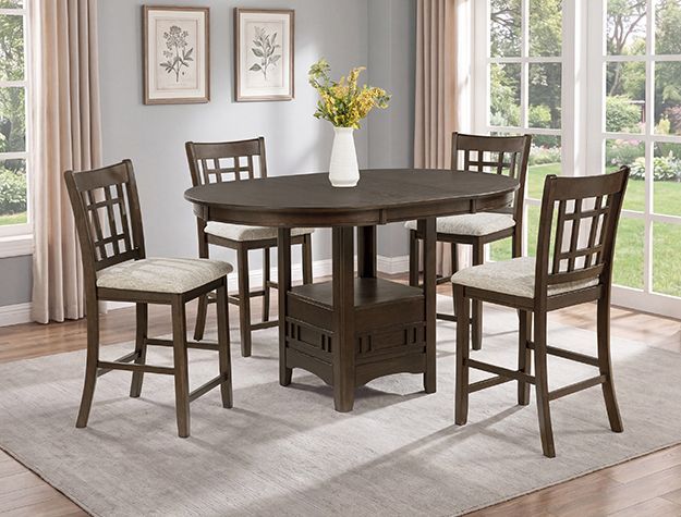 Dark wood dining table with four chairs in a bright room, with flowers in a vase on top.