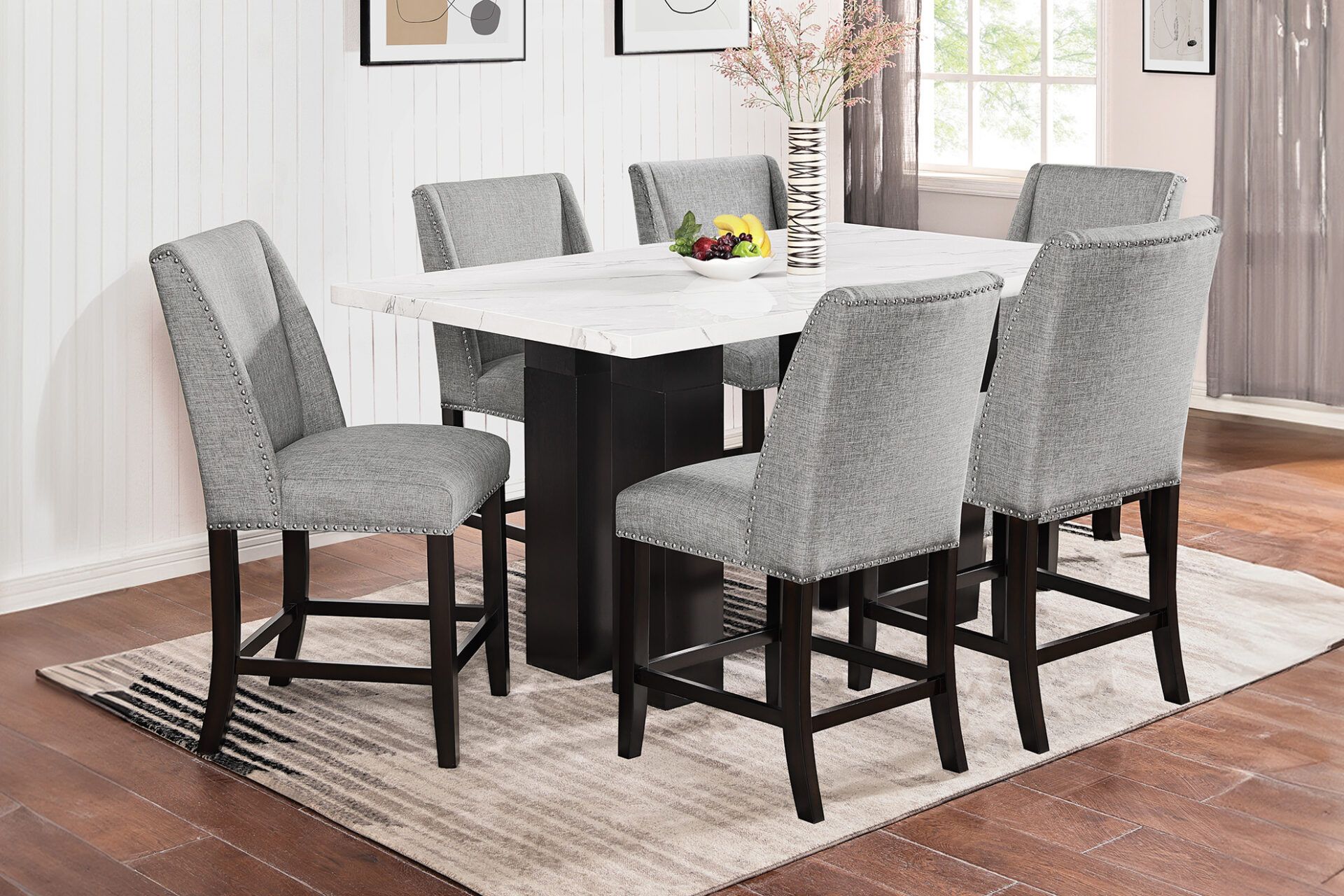 Dining room with a white table, gray chairs, and a beige rug on hardwood floors.