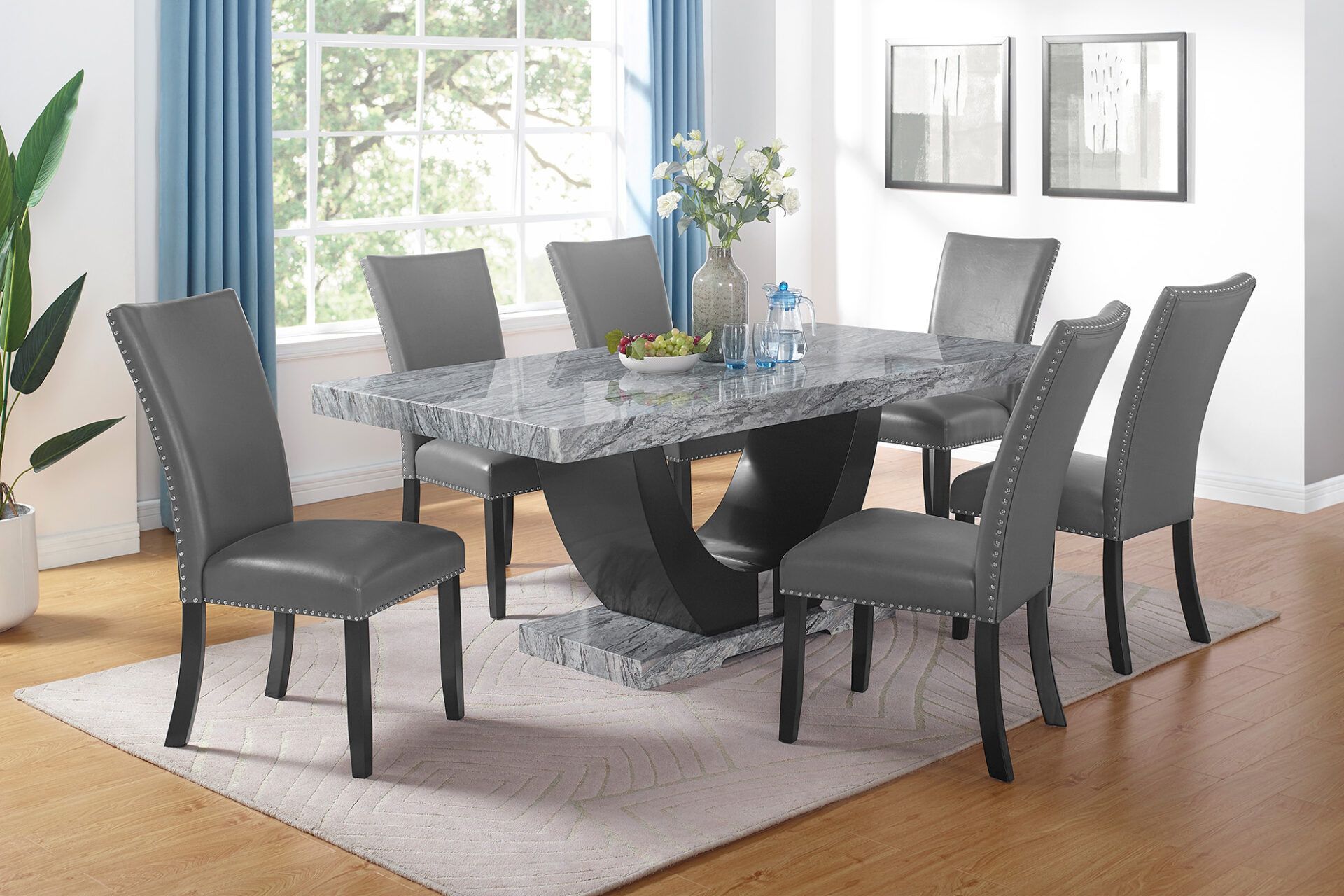 Dining room with a glass-top table, six dark chairs, and blue curtains by a bright window