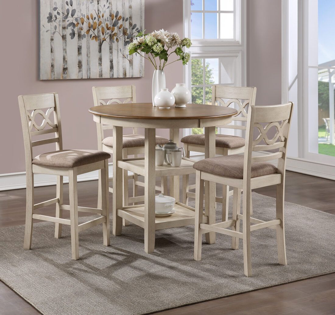Round wood dining table with four cream chairs and a vase of flowers in a bright room