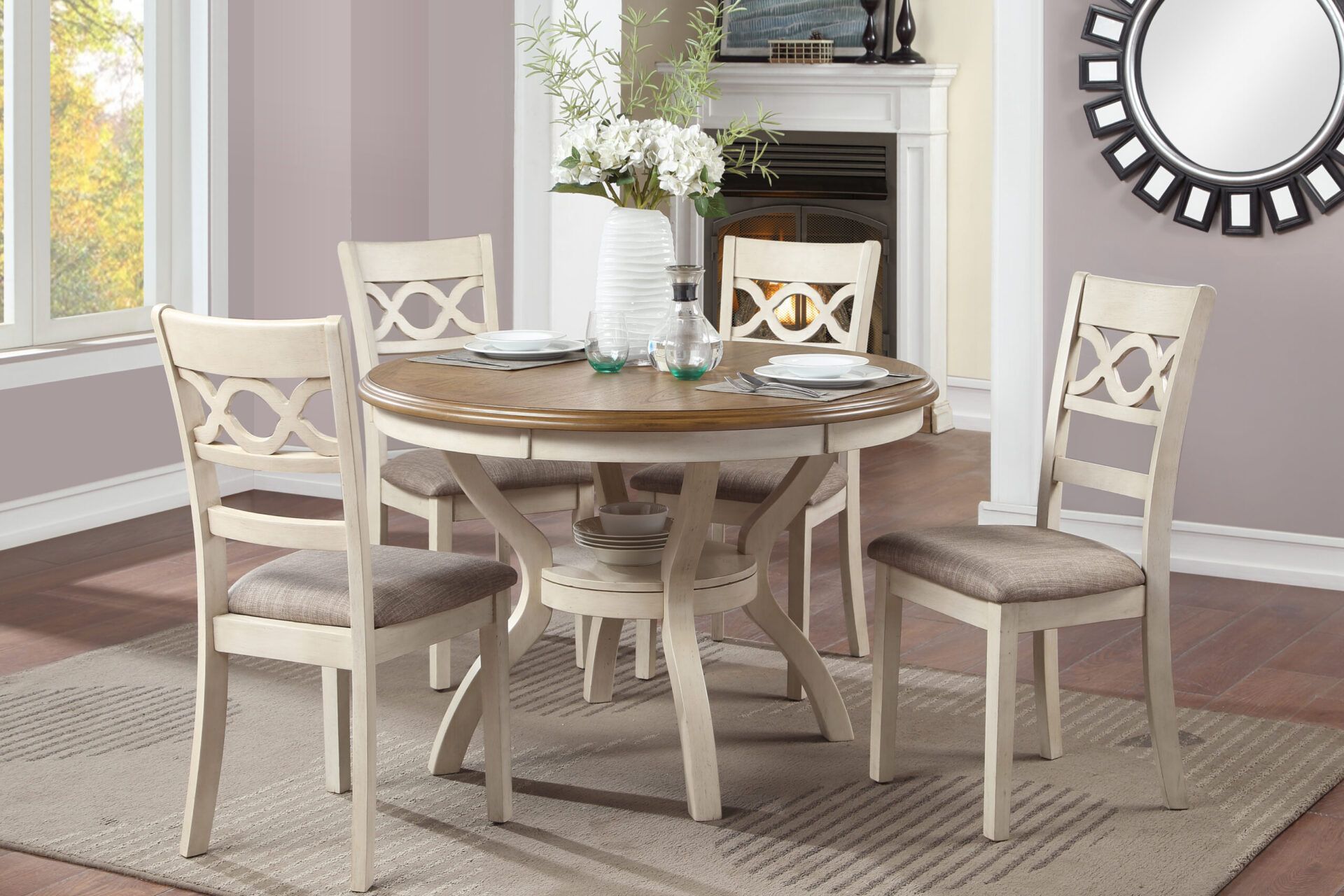 Round wooden dining table with four upholstered chairs in a bright living room