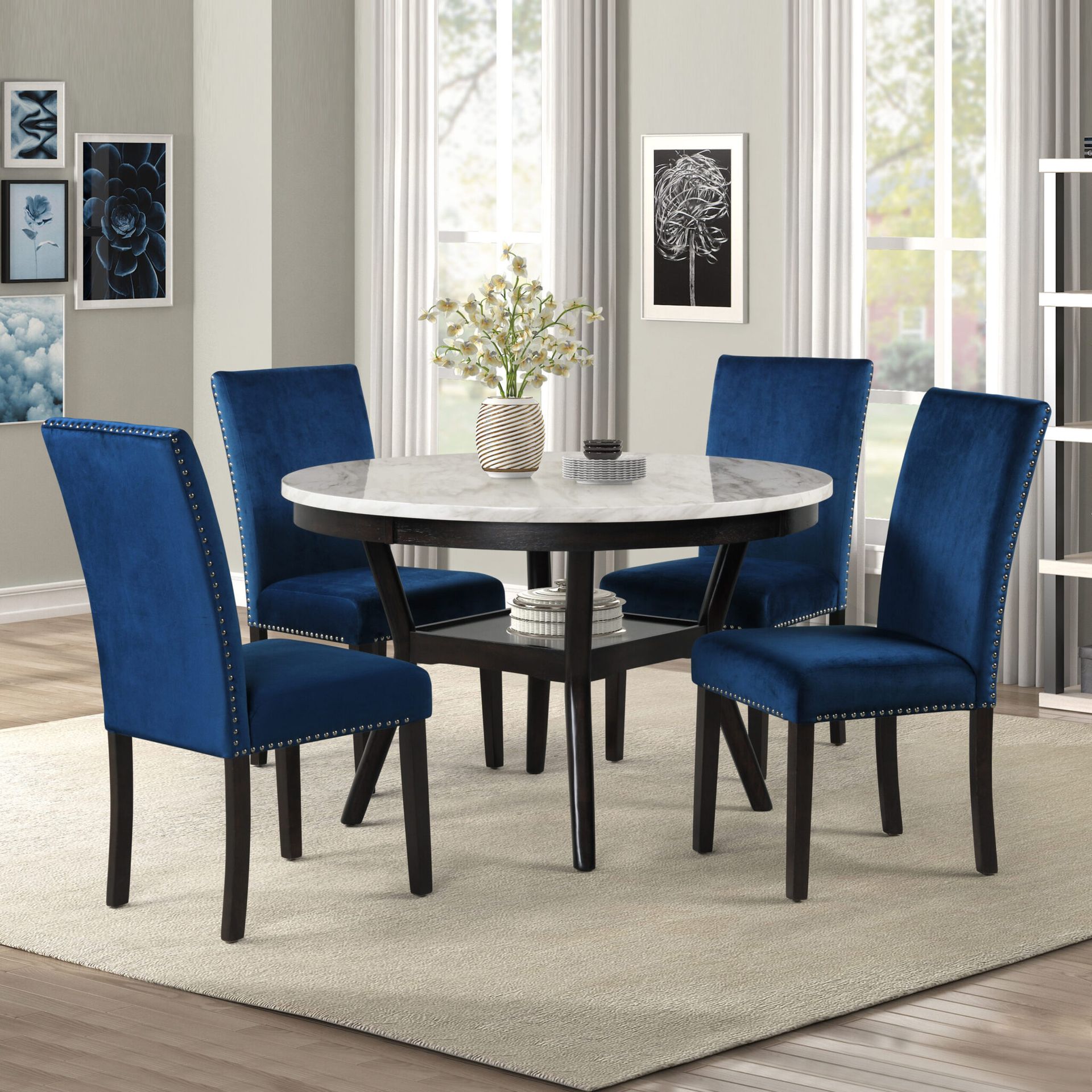 Blue dining chairs around a round table with vase centerpiece in a bright dining room