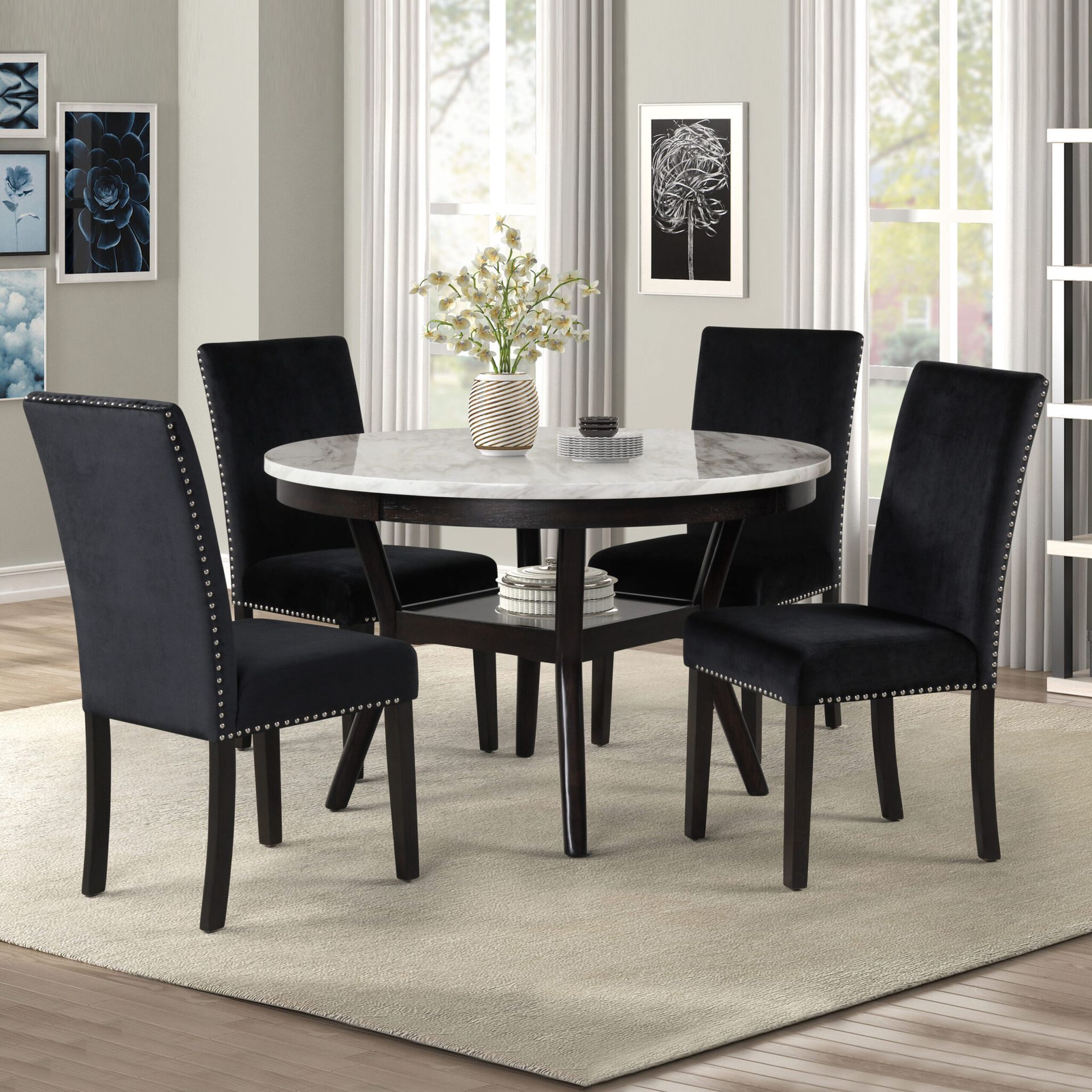 Round marble dining table with four black chairs on a light rug in a bright room