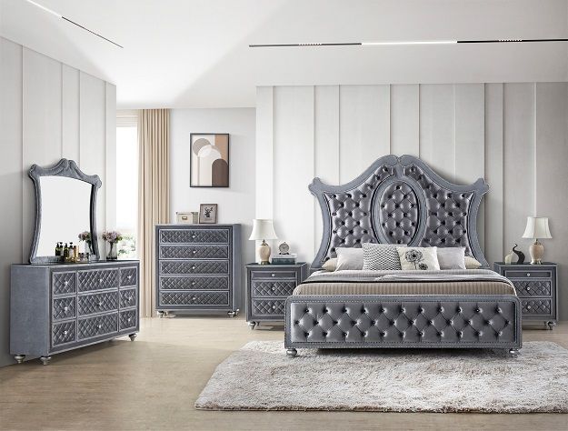 Gray tufted bedroom set with ornate bed, dresser, nightstands, mirror, and rug in a bright room