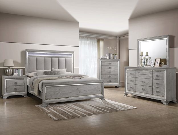 Light gray bedroom set with bed, nightstands, dresser, mirror, and rug in a bright room