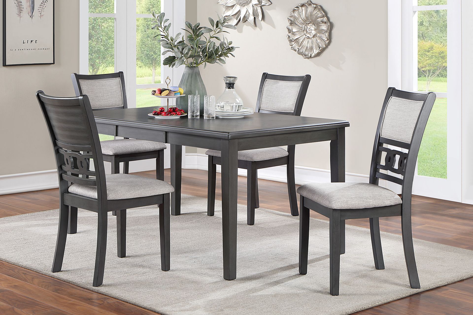 Dark gray dining table with four chairs on a light rug in a bright living room