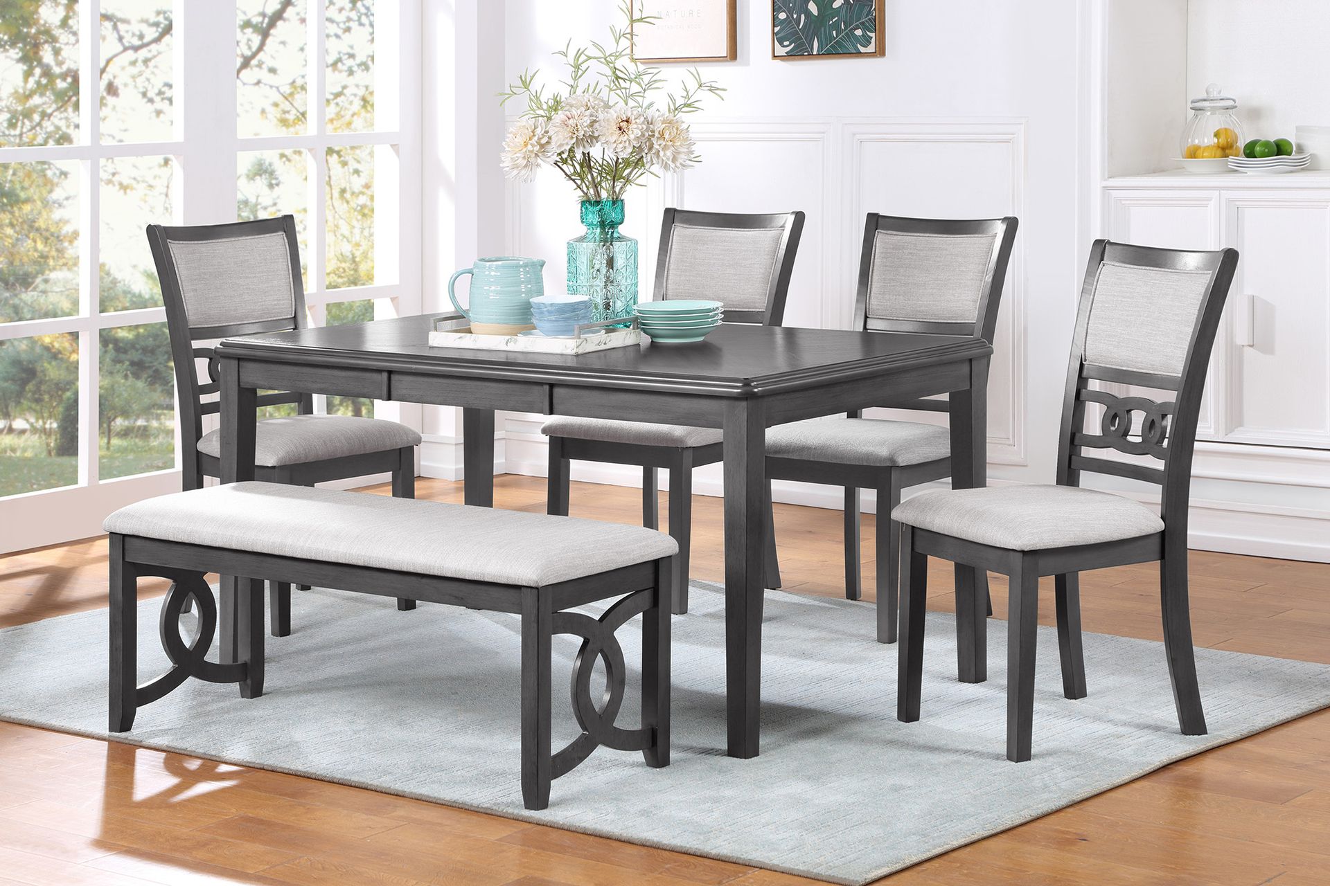 Dining set with dark gray table, chairs, and bench on a light rug in a bright room