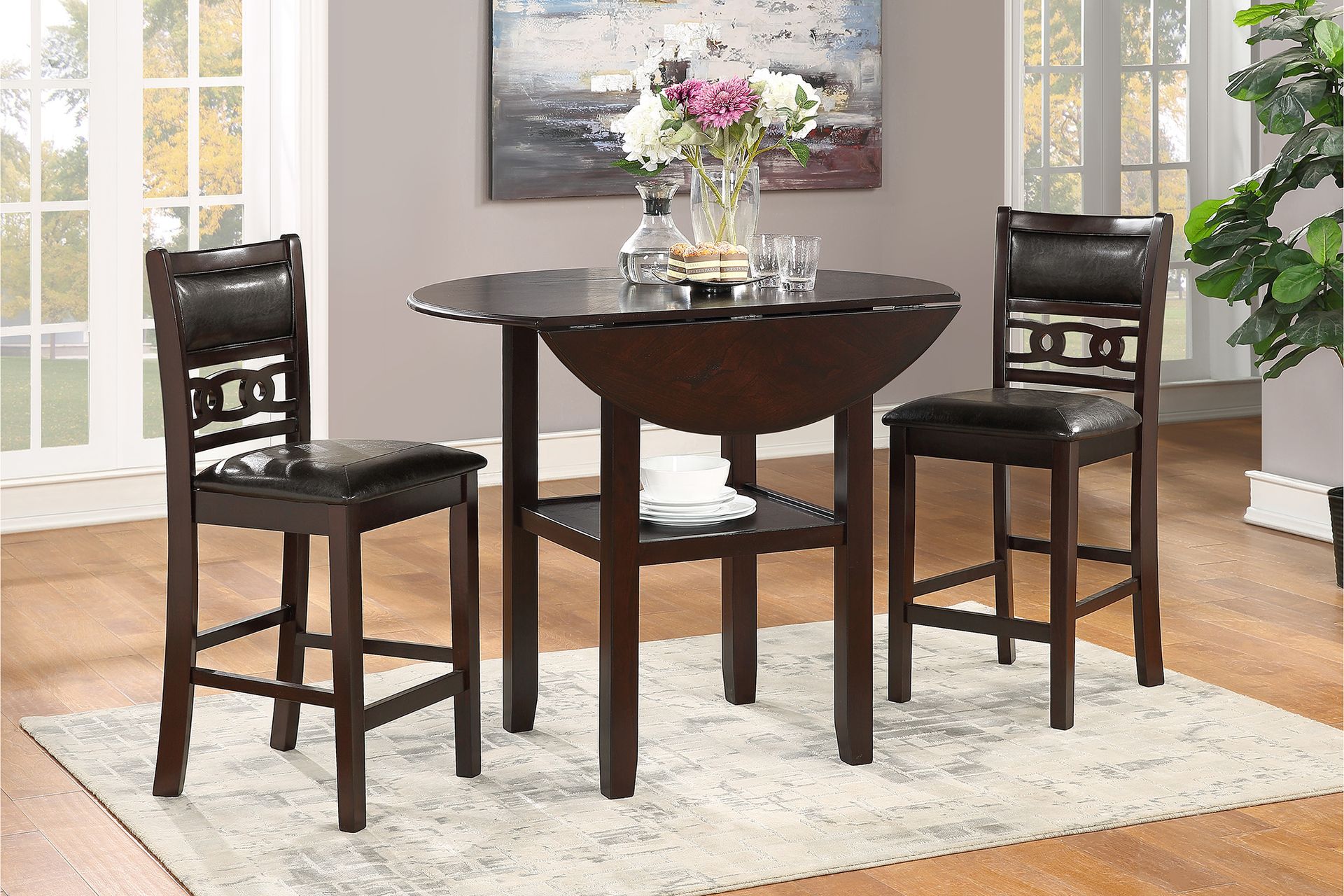 Small dark wood dining set with round table and two chairs on a light rug in a bright room.